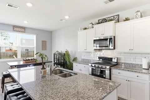 Granite island with sink and a white subway tile backsplash
