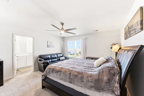 Primary bedroom with a ceiling fan and en suite bath