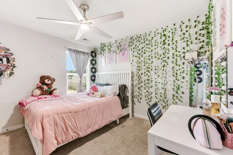Secondary bedroom with a ceiling fan and natural light